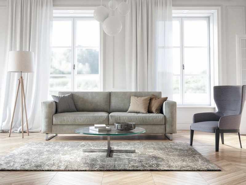 Grey sofa and chair in living room with coffee table and large window
